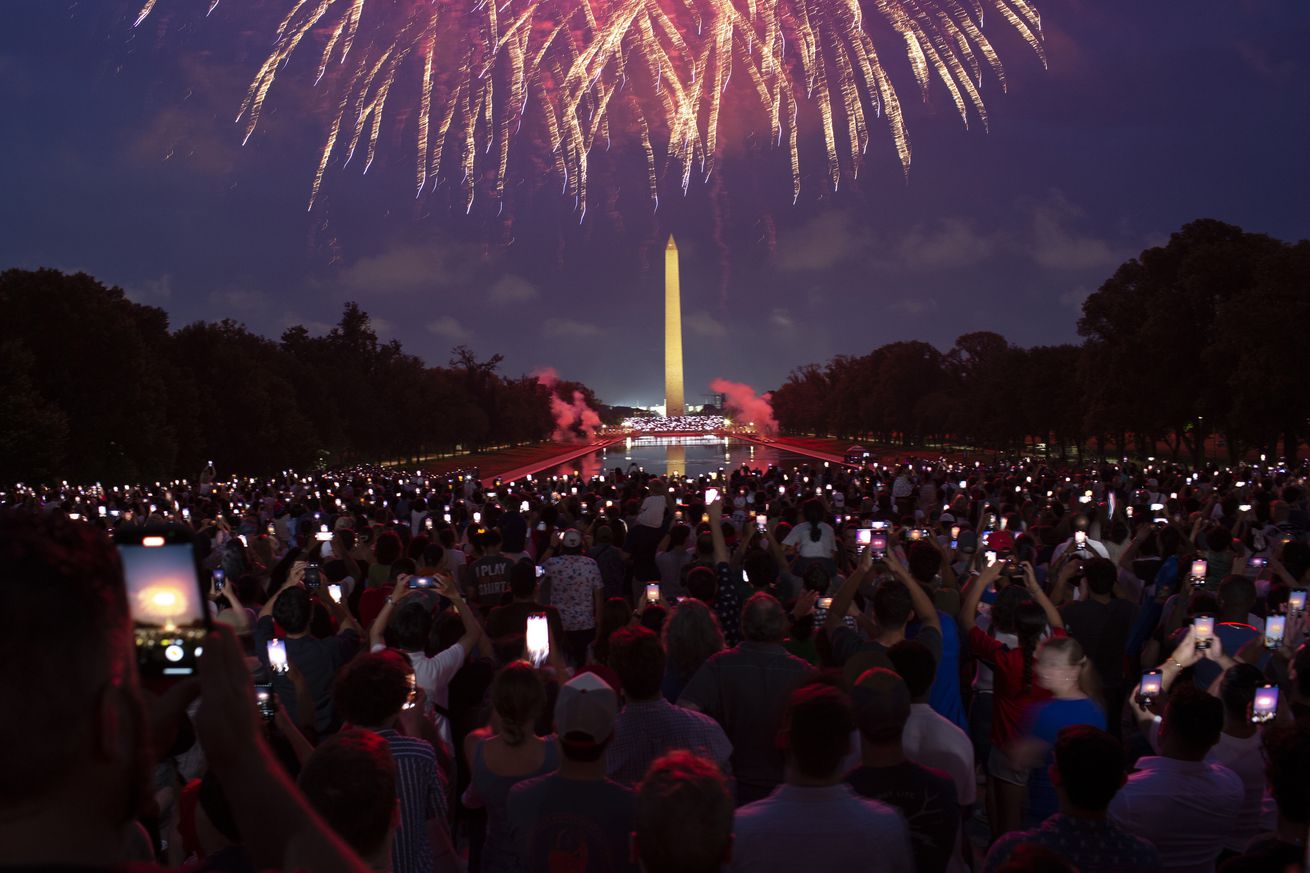 Attendees watch the Independence Day fireworks display along...